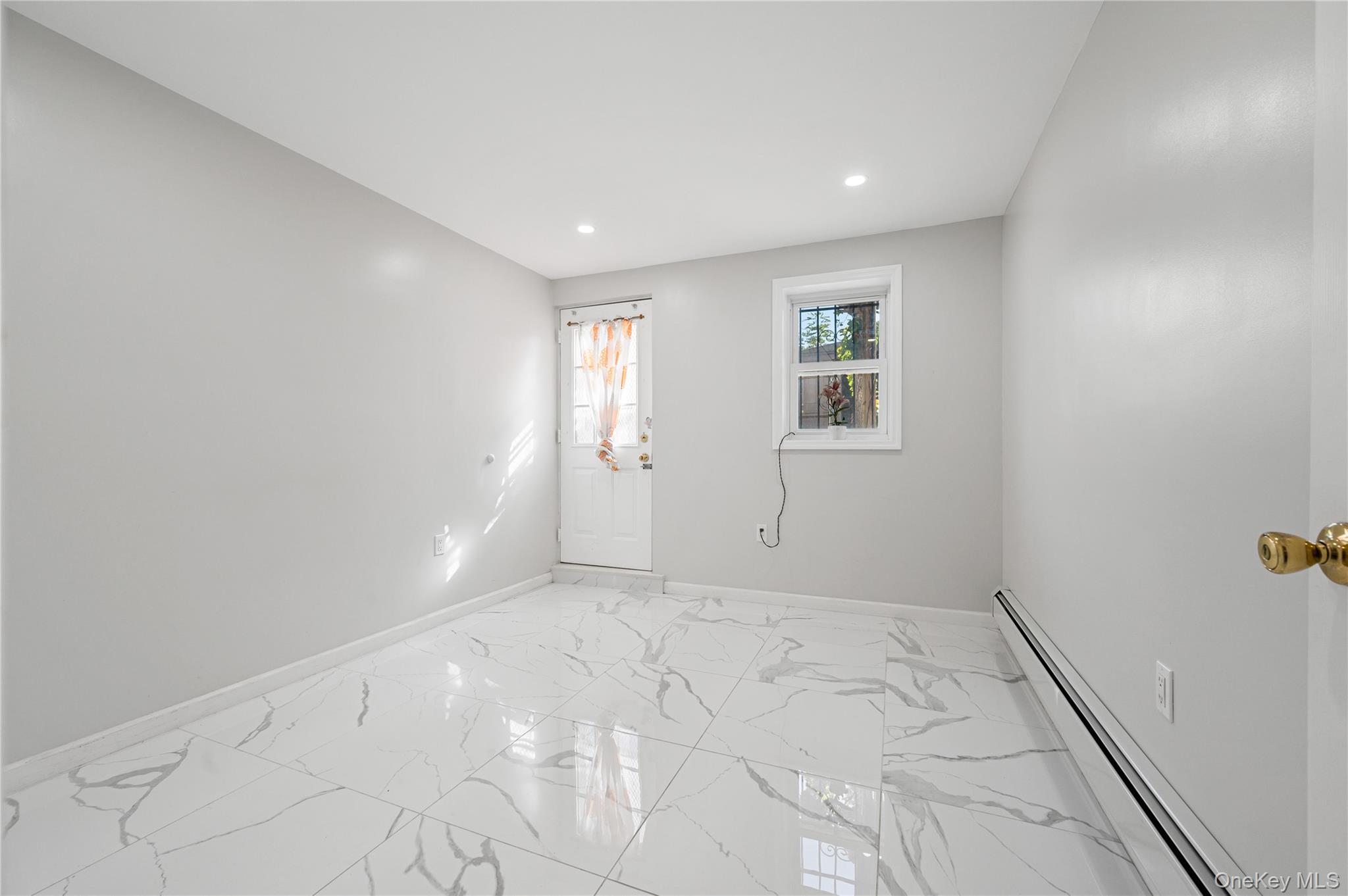 152-10 Peck Avenue Queens, NY 11355 - Photo 15 of 26 Unfurnished room featuring a baseboard heating unit, light marble finish floors, and recessed lighting