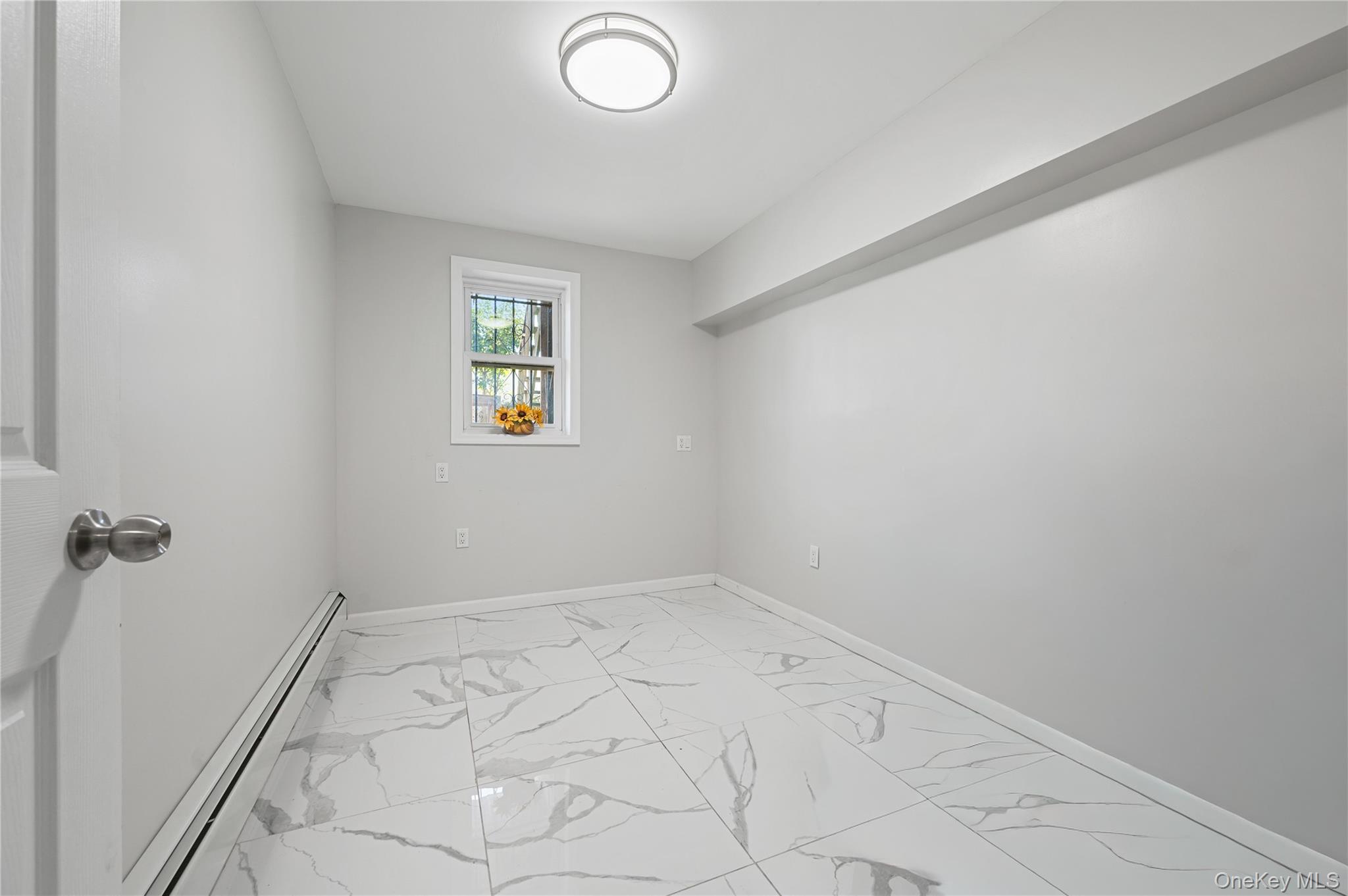152-10 Peck Avenue Queens, NY 11355 - Photo 16 of 26 Spare room with light marble finish floors and a baseboard heating unit