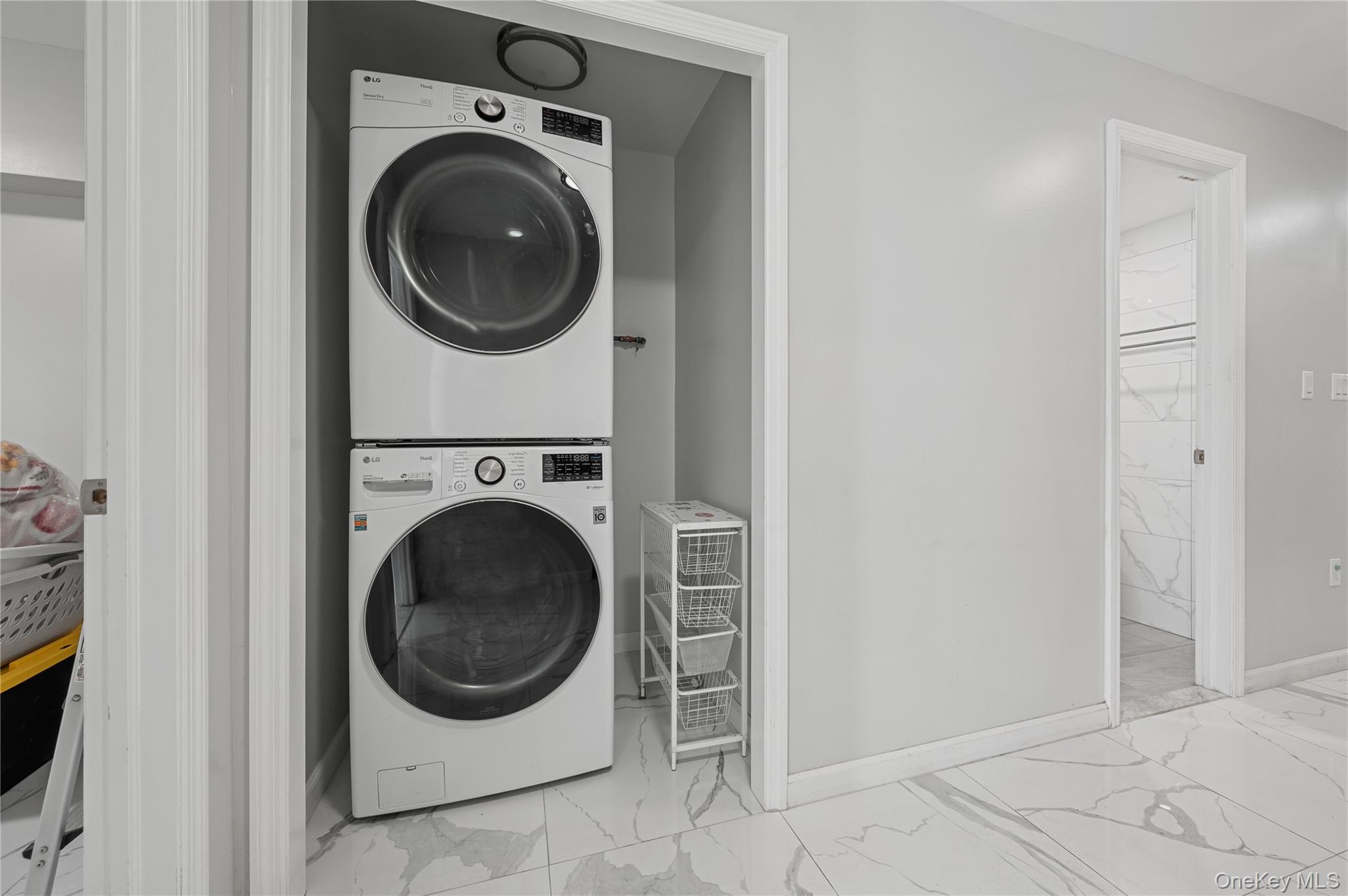 152-10 Peck Avenue Queens, NY 11355 - Photo 20 of 26 Laundry room featuring light marble finish flooring and stacked washing machine and dryer