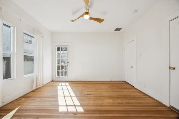 a view of empty room with wooden floor and fan