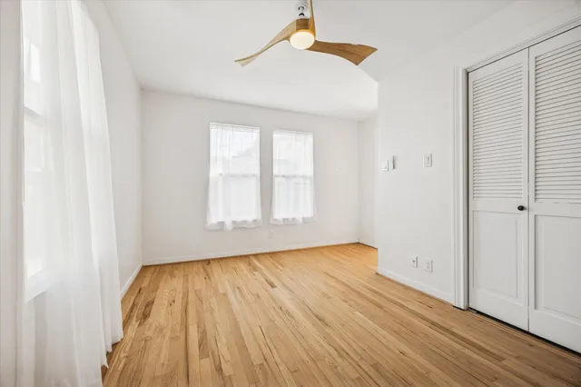 an empty room with wooden floor cabinet and windows