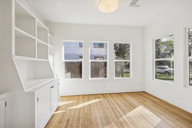 a view of an empty room with wooden floor and window
