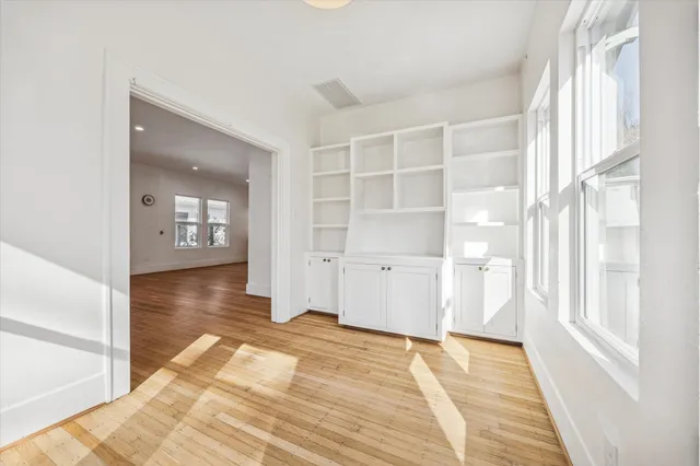 a view of empty room with wooden floor and windows