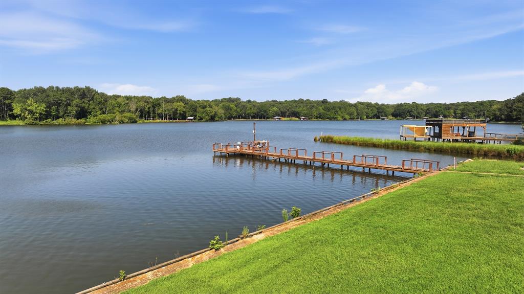 91 Private Road Pittsburg, TX 75686 - Photo 20 of 26 Expansive lakeside property featuring a manicured lawn, a private wooden dock, and a waterfront boathouse with a covered deck