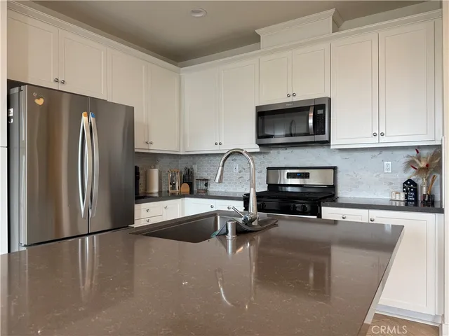 a kitchen with stainless steel appliances a refrigerator a sink a stove a microwave and cabinets