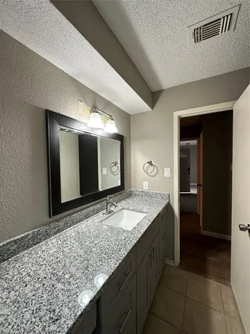 a bathroom with a granite countertop sink and a mirror