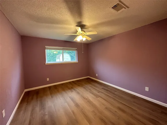 an empty room with a window and a fan