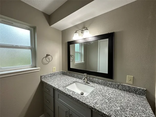 a bathroom with a granite countertop sink and a mirror