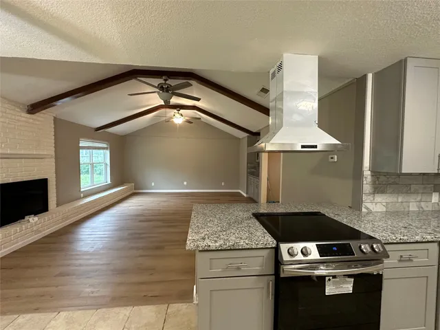 a kitchen with granite countertop a stove and a wooden floors