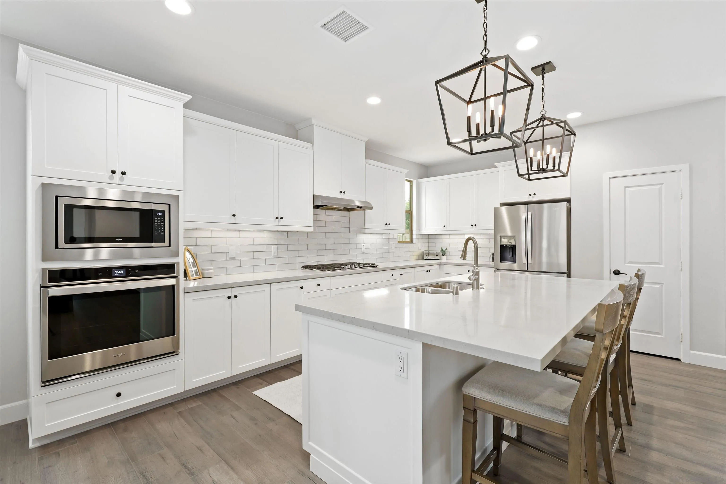 655 Gemstone Drive San Marcos, CA 92078 - Photo 11 of 48 a kitchen with stainless steel appliances a white table chairs and a wooden floor