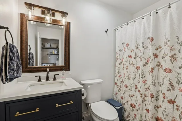 a bathroom with a granite countertop sink a toilet and a mirror