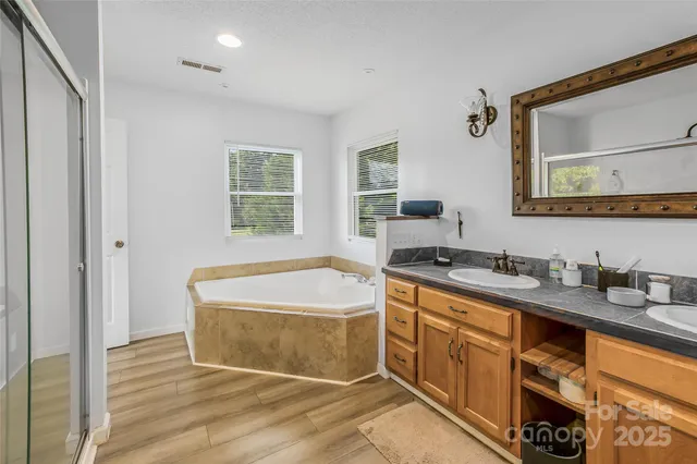 a spacious bathroom with a tub sink and mirror