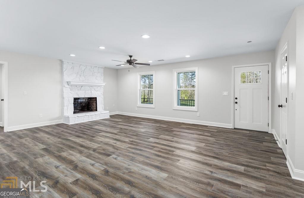 3077 Alec Mountain Road Clarkesville, GA 30523 - Photo 11 of 35 an empty room with wooden floor fireplace and windows