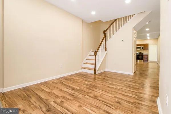 a view of an empty room with wooden floor and stairs