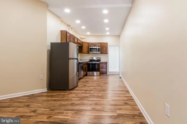 a view of an empty room with wooden floor and entryway