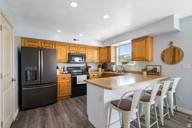 1393 West 150 North Springville, UT 84663 - Photo 10 of 31 Kitchen featuring light wood cabinetry, dark gray appliances, wood-finish flooring, recessed lighting, and a breakfast bar with paneling