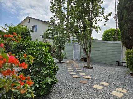a backyard of a house with lots of flowers and trees