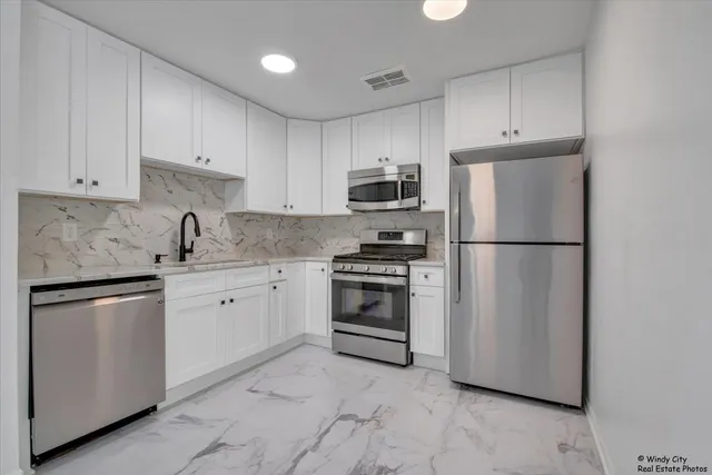 a kitchen with stainless steel appliances granite countertop a refrigerator sink and white cabinets