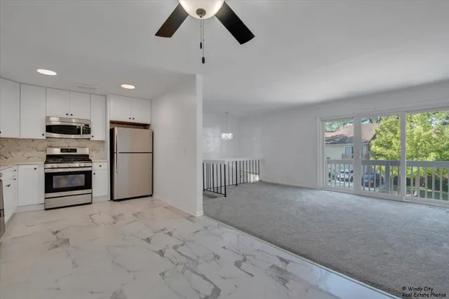 a kitchen with stainless steel appliances kitchen island granite countertop a refrigerator oven a stove with white cabinets and wooden floor