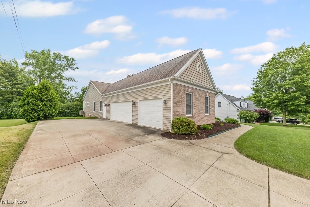 369 Eldridge Road Aurora, OH 44202 - Photo 41 of 50 View of property exterior with brick siding, a garage, driveway, a lawn, and a shingled roof