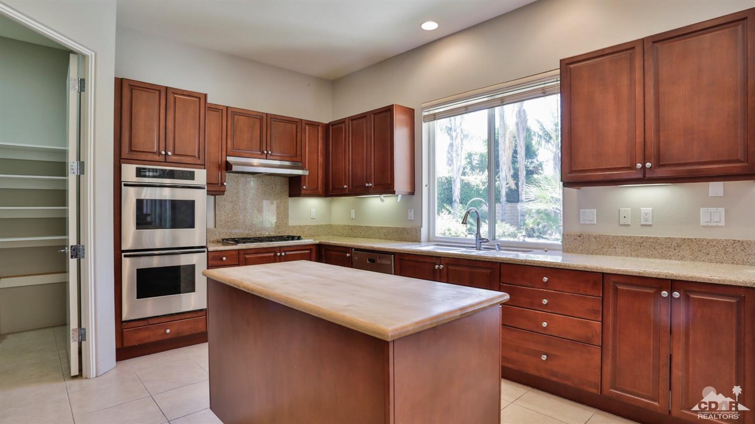 5 University Circle Rancho Mirage, CA 92270 - Photo 15 of 60 a kitchen with wooden cabinets a sink and a stove