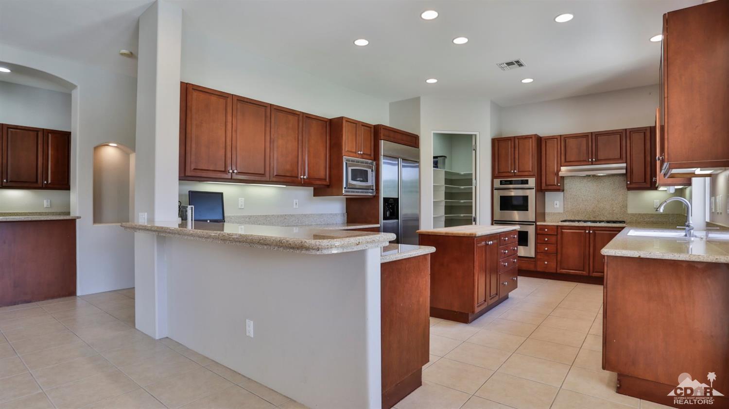 5 University Circle Rancho Mirage, CA 92270 - Photo 10 of 60 a kitchen with stainless steel appliances granite countertop wooden cabinets a stove a sink and a refrigerator