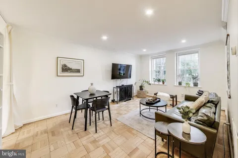 a living room with furniture two large window and a flat screen tv