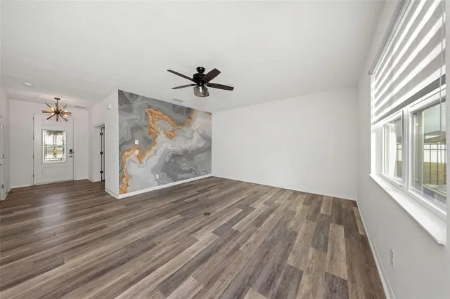 a view of empty room with wooden floor and kitchen view