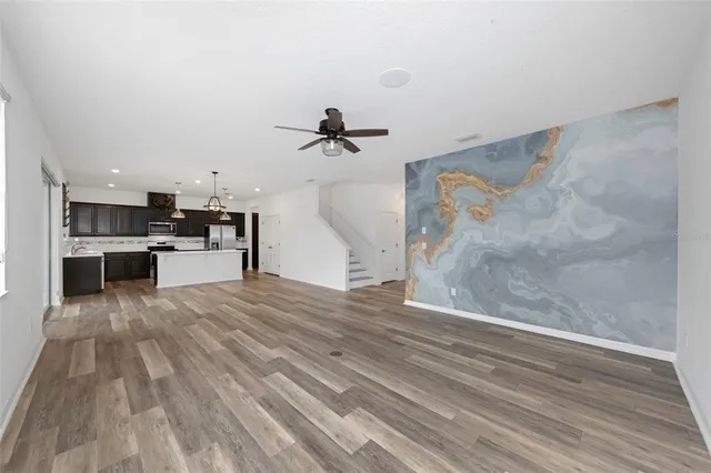 a kitchen with stainless steel appliances kitchen island granite countertop a refrigerator a oven a sink and a wooden floor