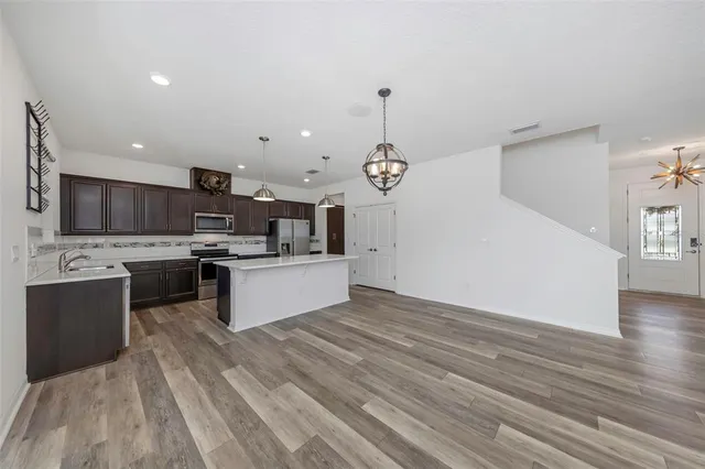 a kitchen with stainless steel appliances a sink dishwasher a stove top oven a refrigerator and island with wooden floor