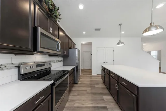 a kitchen with stainless steel appliances a stove a refrigerator and a sink with wooden floor