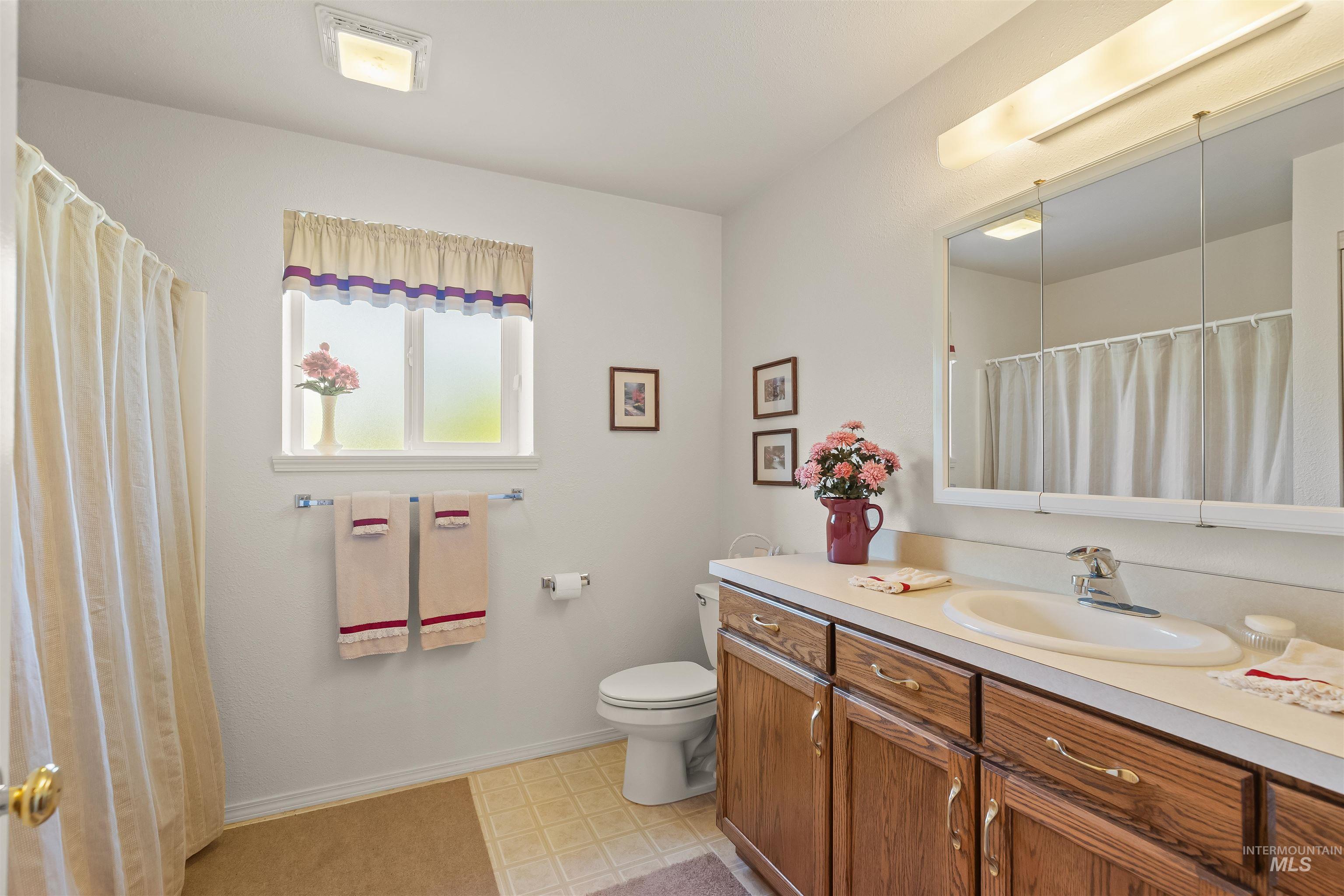 743 Wall Crk Road Stites, ID 83552 - Photo 41 of 48 Bathroom featuring a wood-finish vanity with a built-in sink, a full-length mirrored medicine cabinet, and a shower with a curtain rod