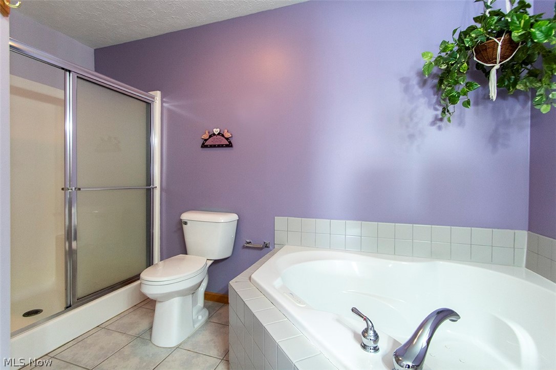 4902 Foote Road, Unit 21 Medina, OH 44256 - Photo 17 of 34 Bathroom featuring tile flooring, a textured ceiling, toilet, and independent shower and bath