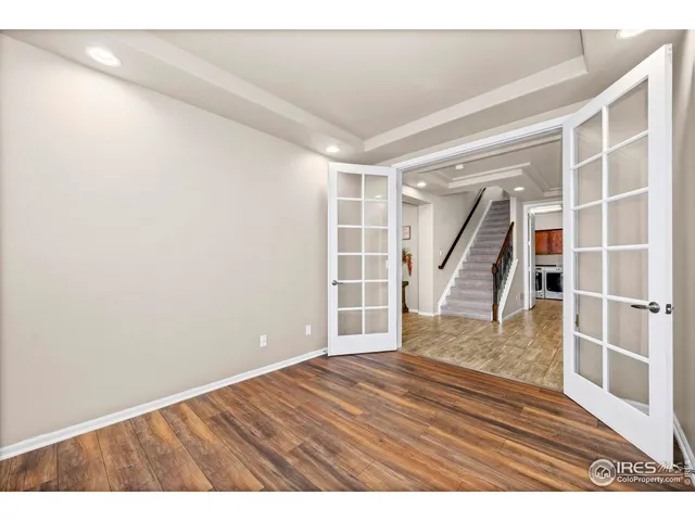 a view of an empty room with wooden floor and stairs