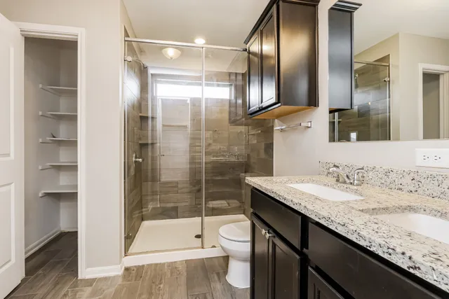 a bathroom with a granite countertop sink a toilet and shower