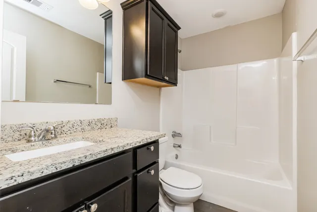 a bathroom with a granite countertop sink toilet and a mirror