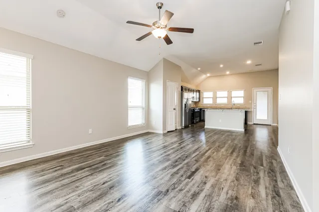 a view of a kitchen with a stove cabinets a ceiling fan and wooden floor