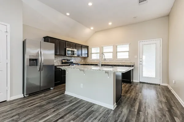 a kitchen with stainless steel appliances granite countertop a refrigerator a sink a stove and oven