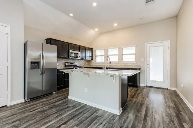 a kitchen with stainless steel appliances granite countertop a refrigerator a sink a stove and oven