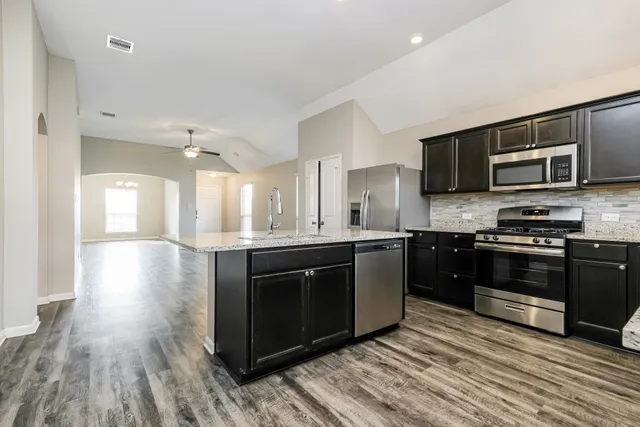 a kitchen with stainless steel appliances kitchen island granite countertop a stove top oven and sink