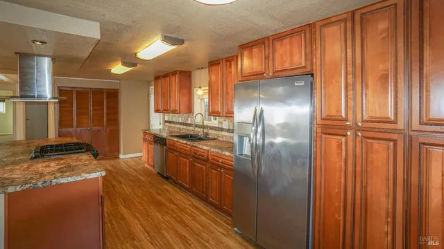 a kitchen with stainless steel appliances granite countertop a refrigerator a stove and a sink