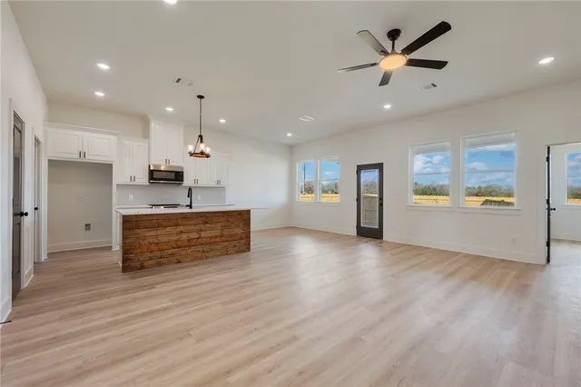 a view of a hallway with wooden floor and a bathroom
