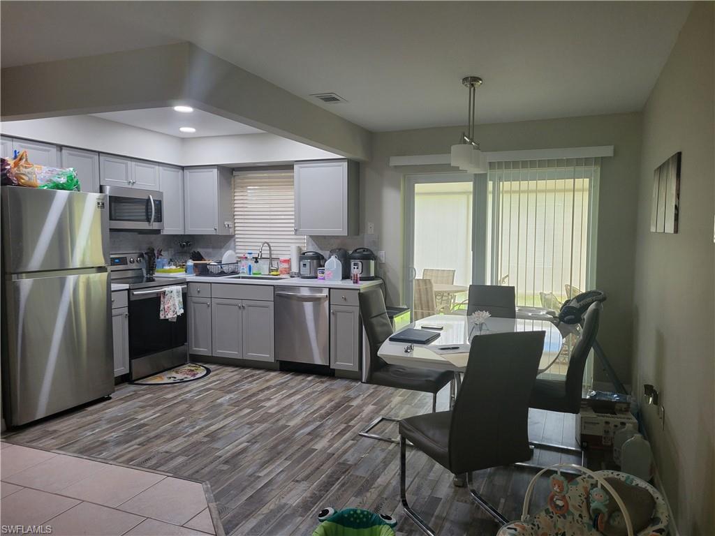 8518 Morris Road Fort Myers, FL 33967 - Photo 10 of 18 a kitchen with a refrigerator a sink dishwasher a dining table and chairs with wooden floor
