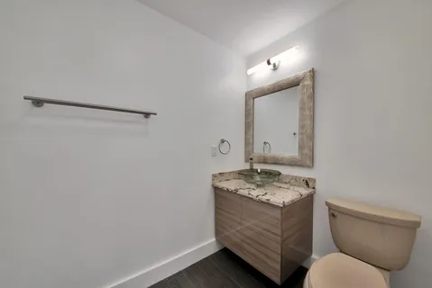 a bathroom with a granite countertop sink a toilet and mirror