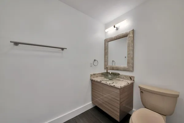 a bathroom with a granite countertop sink a toilet and mirror