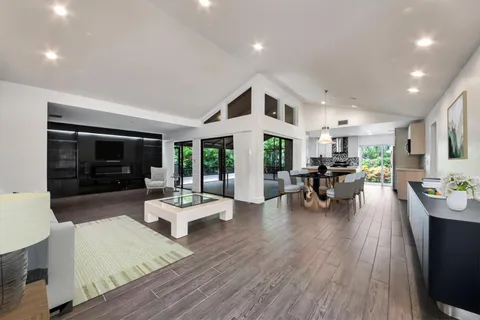 a living room with furniture floor to ceiling window and wooden floor