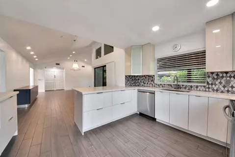 a kitchen with stainless steel appliances kitchen island granite countertop a stove a sink and white cabinets with wooden floor