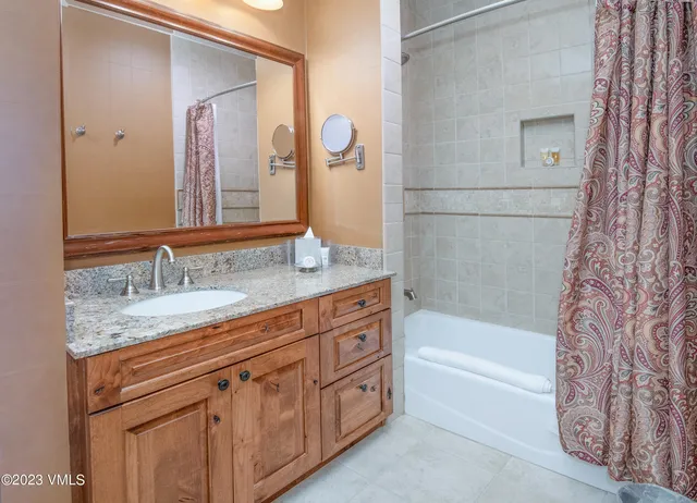 a bathroom with a granite countertop tub sink and mirror