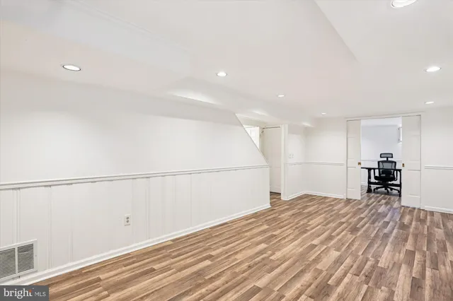 a large white room with wooden floor and furniture