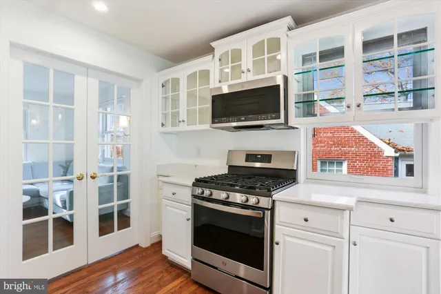 a kitchen with cabinets stainless steel appliances and wooden floor
